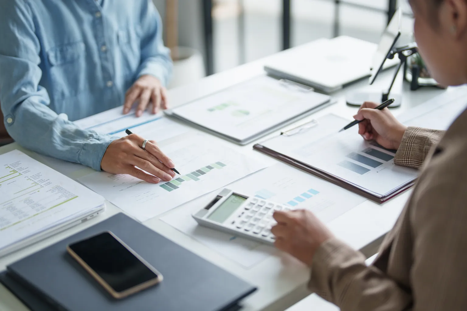 Two people reviewing financial bar charts and using a calculator